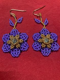 purple and gold beaded flower earrings on a red background