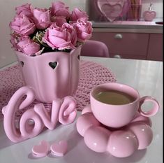 a cup of coffee and some pink roses on a table