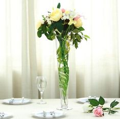 there is a vase with flowers on the table next to two empty wine glasses and silverware