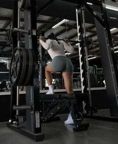 a woman is squatting on a weight machine