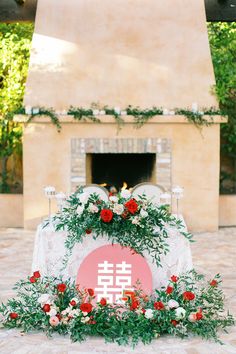 an outdoor ceremony with flowers and greenery around the fire place in front of a fireplace