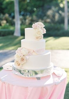 a wedding cake sitting on top of a table covered in pink and white cloths