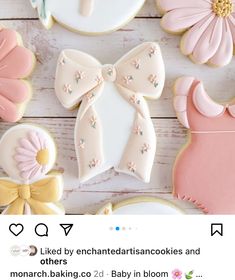 some decorated cookies are sitting on a white wooden table with pink and yellow flowers in the background