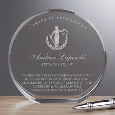 an award plaque on a table with a pen and ballpoint pen next to it