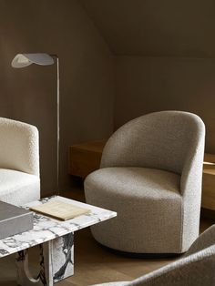 a living room with two chairs and a table in the corner, one chair has a book on it