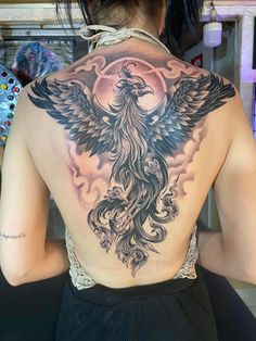 the back of a woman's tattoo with an eagle and moon on her shoulder