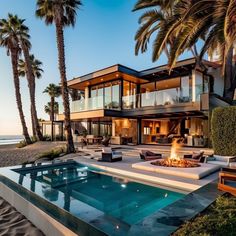 an outdoor fire pit in front of a large house with palm trees on the beach