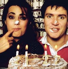 a man and woman standing in front of a birthday cake with candles on it that says 25