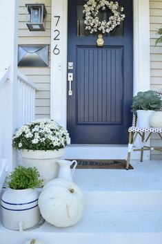 the front door is decorated with white pumpkins and flowers