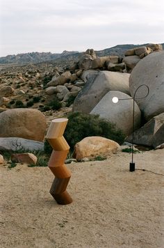 a sculpture in the middle of a desert with large rocks behind it and a light on top