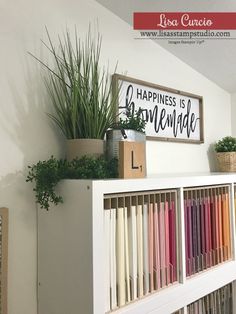 a shelf with books and plants on top of it in front of a sign that says happiness is homemade