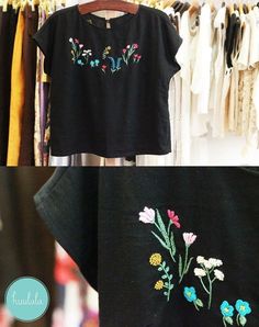 an embroidered t - shirt hanging on a rack next to other clothes and clothing racks