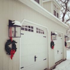 two garages with wreaths on the doors and snow on the ground around them