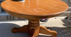 a wooden table sitting on top of a sidewalk next to a building with an electric outlet plugged into it