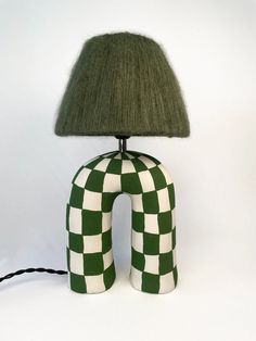 a green and white checkered lamp sitting on top of a table