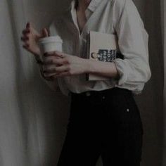 a woman holding a coffee cup in her right hand while standing next to a curtain