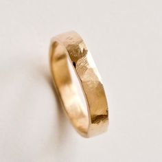 A hammered  gold ring which would be great as a unique wedding band. I start by making the band from 14 carat yellow gold and then hammer it by hand to create irregular indents and a rustic texture. I use a flat shape hammer that strikes the metal at slightly different angles and gives a really unique asymmetrical shape. The subtle ridged surface texture is also transferred onto the metal  which reminds me of naturally weathered stone. The photos shown here are 3mm and 4mm widths. They are 1.3-1 Hand Forged 14k Gold Engraved Wedding Ring, Minimalist Engraved Hammered Wedding Ring, Hammered 14k Gold Wedding Band, 14k Gold Hammered Wedding Rings, Hammered 14k Gold Wedding Rings, Hammered Round Band Wedding Rings, Hammered 14k Gold Engraved Wedding Ring, Yellow Gold Hammered Wedding Ring, Gold Hammered Bands For Promise Ring