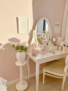 a white vanity table with a mirror and flowers on it in front of a window