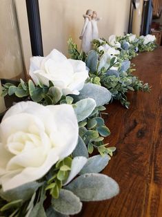 white flowers and greenery are lined up on a table in front of a mirror