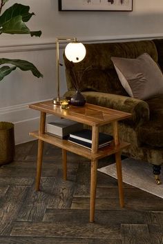 a wooden table with a lamp on it next to a couch and potted plant