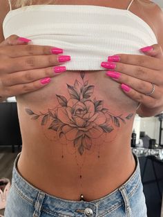 a woman's stomach with a flower tattoo on her belly and pink nail polish