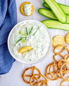 a bowl of dip surrounded by pretzels, crackers and celery