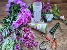 flowers, scissors and other crafting supplies laid out on a wooden table with purple flowers