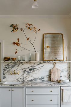 a kitchen with marble counter tops and gold accents on the wall, along with white cabinets