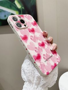 a woman holding up her phone case with pink flowers on it