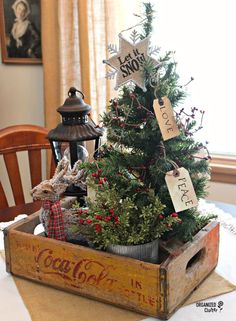 a small christmas tree in a wooden crate on top of a table with other decorations