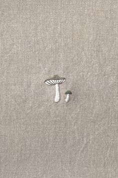 an image of a mushroom on the side of a gray fabric material with two small mushrooms sticking out of it