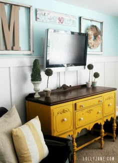 a living room with yellow furniture and pictures on the wall above it's tv