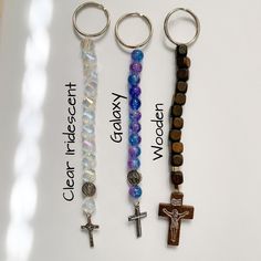 three key chains with beads and crosses on them, one has a cross in the middle