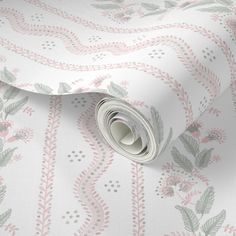 a white and pink wallpaper with floral designs on the bottom, along with a rolled up roll of paper