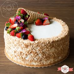 a cake topped with strawberries and flowers on top of a wooden table