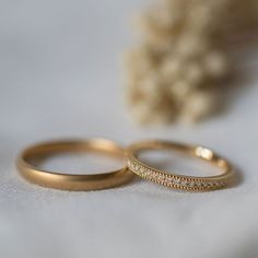 two wedding rings sitting on top of a white cloth