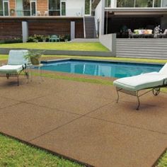 two lawn chairs sitting on top of a patio next to a swimming pool and house