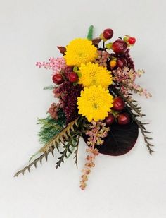 a vase filled with lots of different types of flowers on top of a white surface