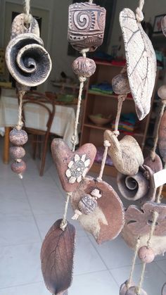 a wind chime hanging from the ceiling with leaves and flowers on it's hooks