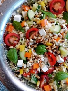 a metal bowl filled with vegetables and grains