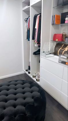 a black ottoman sits in front of a white closet