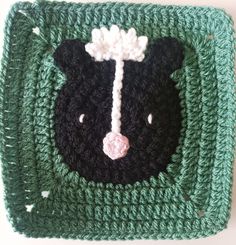 a crocheted square with a black and white bear on it's face