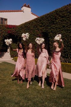 four bridesmaids in pink dresses holding bouquets and posing for the camera on their wedding day