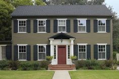 a brown house with black shutters on the front and red door is shown in this image