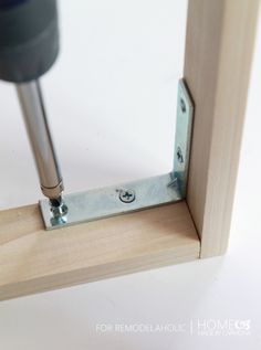 a screwdriver is attached to the side of a wooden frame with metal studs