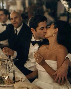 a man and woman kissing at a dinner table