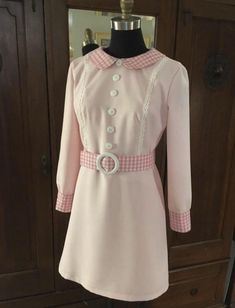 a pink dress on display in front of a wooden cabinet