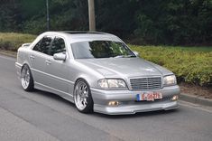 a silver car is parked on the side of the road in front of some bushes