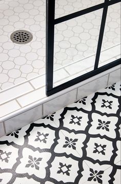 a bathroom with black and white tiles on the floor, shower door and toilet seat