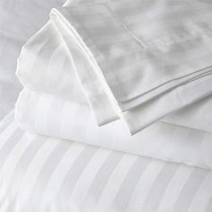 three sheets folded on top of each other in white and grey striped bed linens